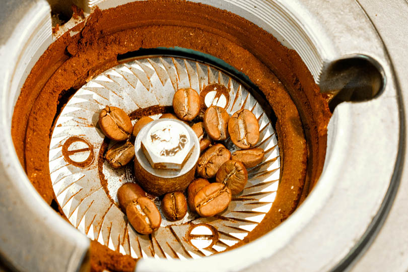 Close-up of a conical burr set removed from a grinder, showing the inner and outer burrs side by side on a wooden surface.