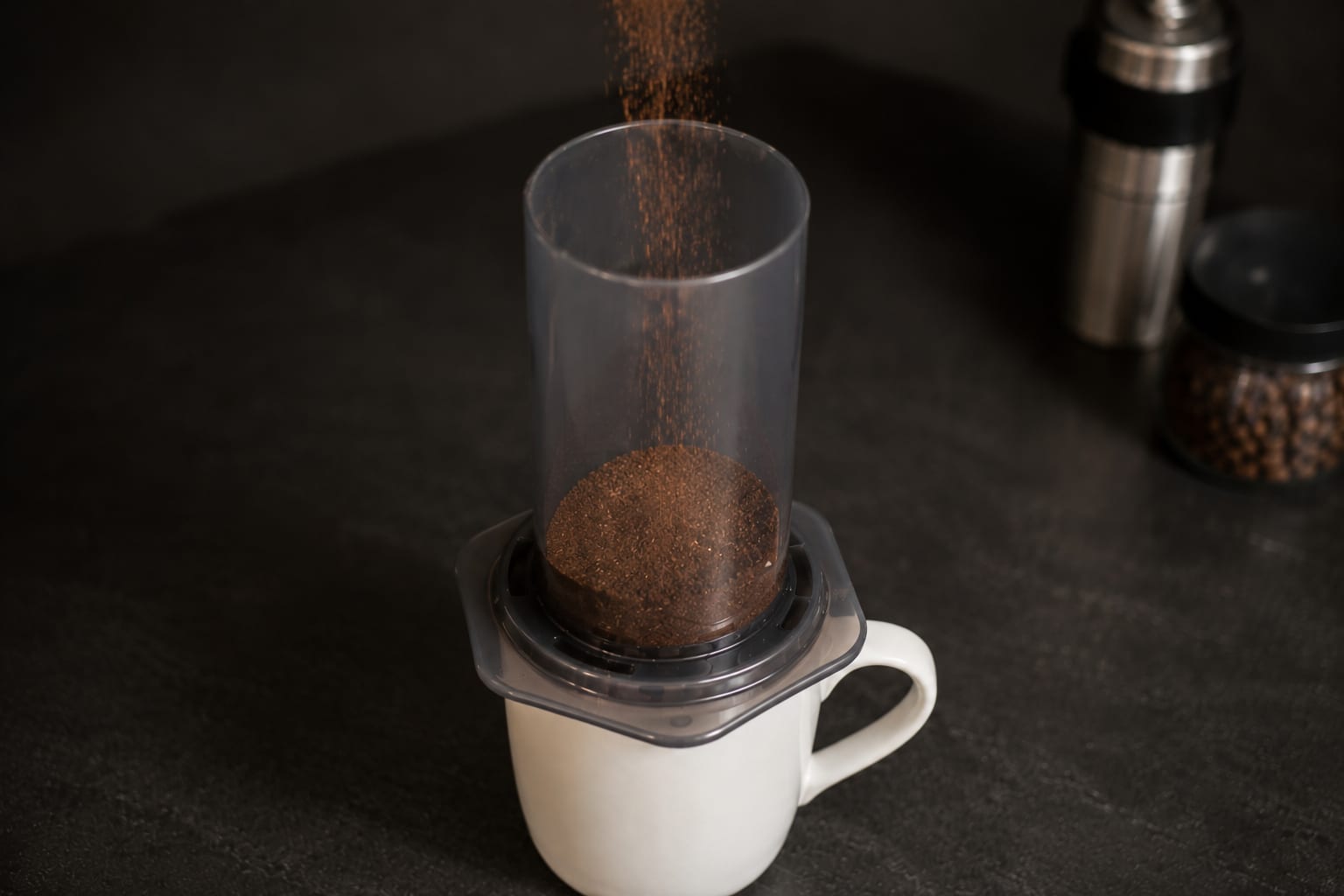 Medium-fine ground coffee pouring into the AeroPress chamber on a mug