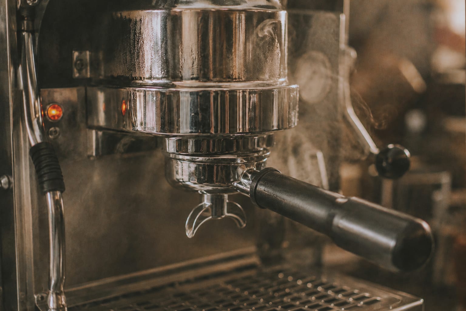 Grupo de máquina de espresso en acero inoxidable con vapor visible, calentándose antes de extraer el shot